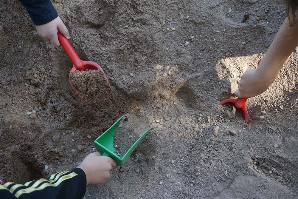 Kinderhände schaufeln im Sand